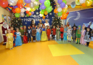 Pani dyrektor Maria Królikowska, p. Arleta, p. Ewa wraz z grupą przebranych dzieci stoi na tle dekoracji.